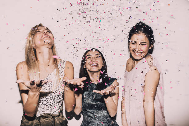 Lady's party Photo of a group of young women celebrating their youth, femininity  and friendship - tossing a confetti in the air while dancing girl power photos stock pictures, royalty-free photos & images