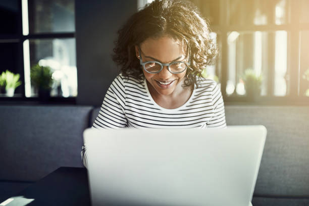 istock Smiling young African sitting at a table browsing the internet 915655628