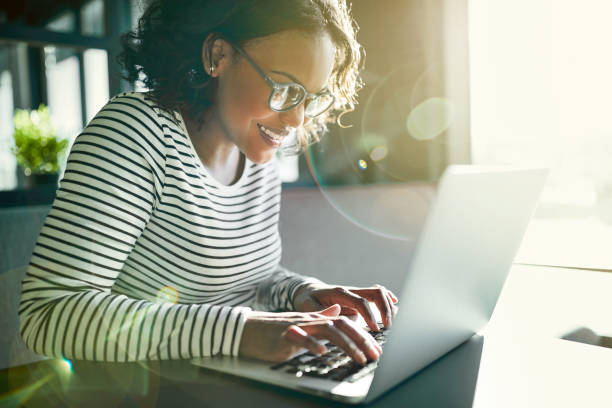 istock Smiling African woman sitting at a table working online 915655698