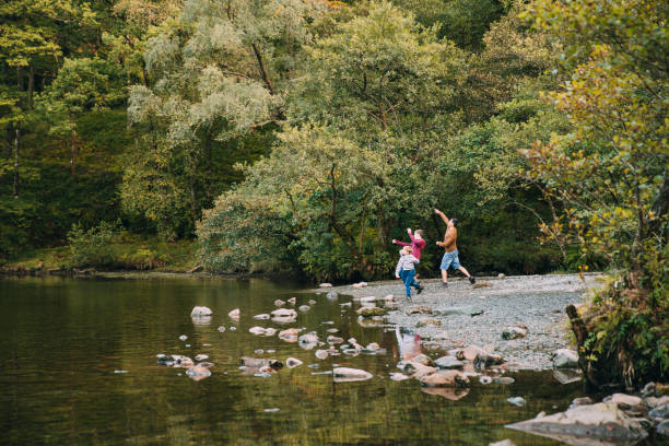 Skimming Stones with Dad Two boys are skimming stones in a lake with their father. keswick stock pictures, royalty-free photos & images