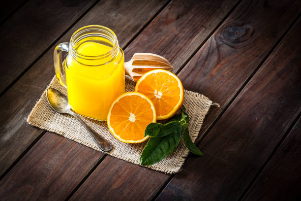 istock Orange juice glass jar shot on rustic wooden table 915657004