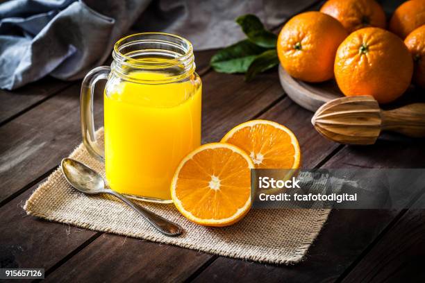 Tarro De Cristal Del Jugo De Naranja En La Rústica Mesa De Madera Foto de stock y más banco de imágenes de Zumo de naranja