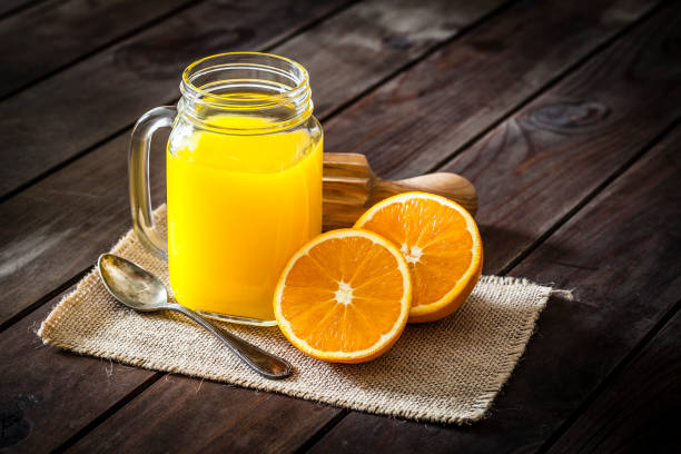 istock Orange juice glass jar shot on rustic wooden table 915657272
