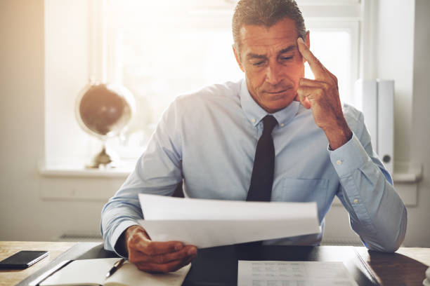 istock Mature businessman reading paperwork at an office desk 915657848