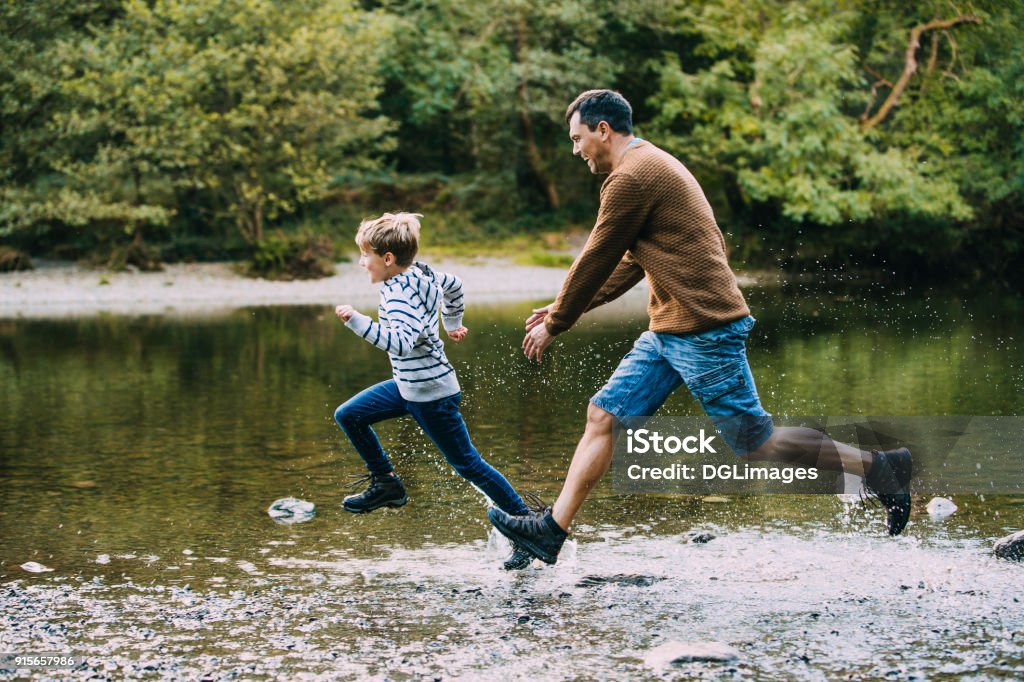 Pourchassés dans de l’eau par papa - Photo de Enfant libre de droits