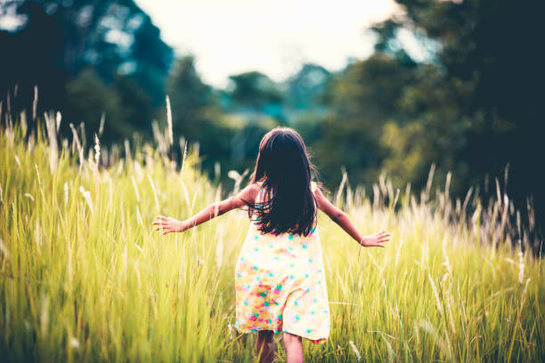 Asian little girl running away in a field outdoors stock photo