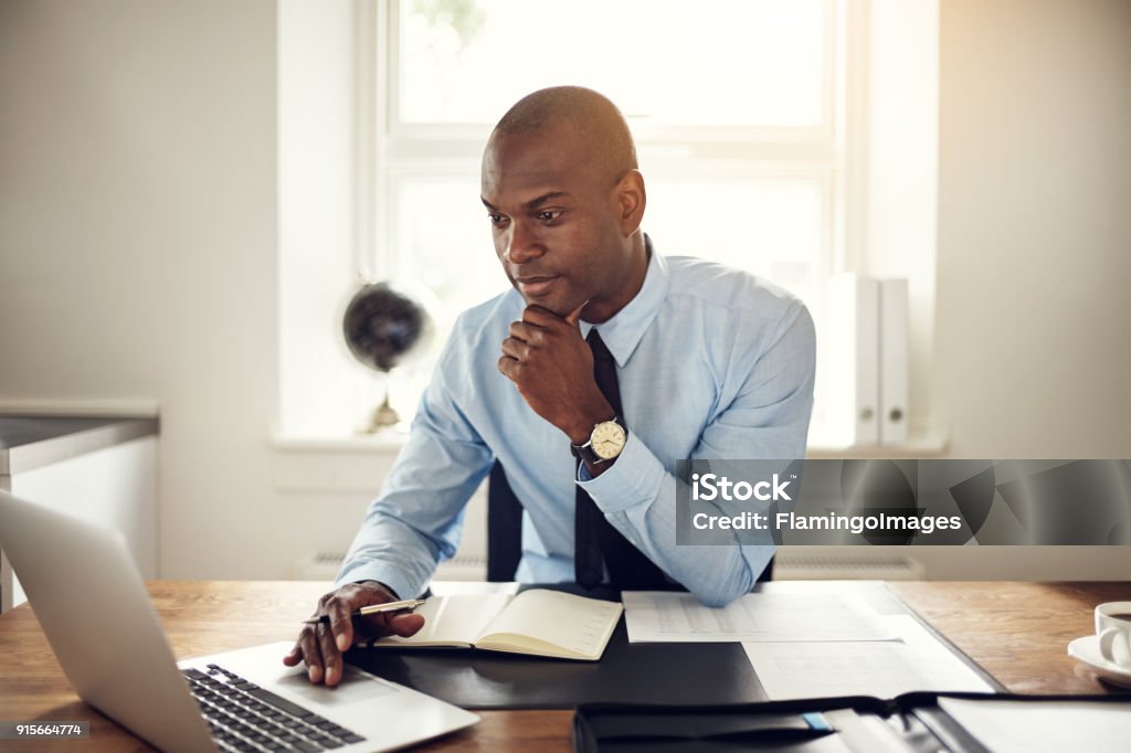 Giovane uomo d'affari che lavora su un laptop in un ufficio - Foto stock royalty-free di Avvocato