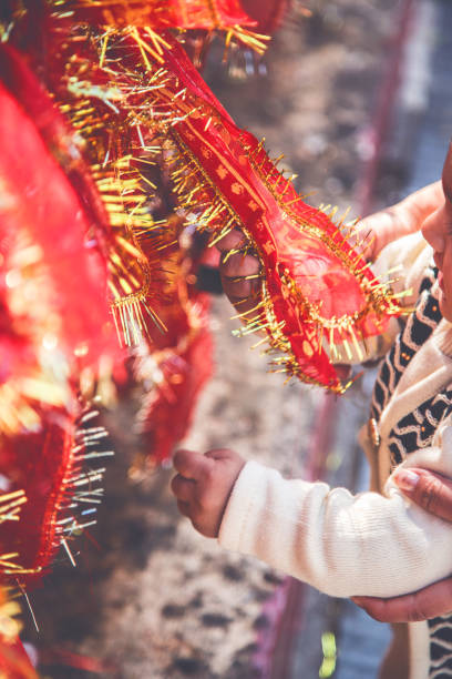 Mother and daughter holding red sacred cloth offered by people during religious ritual in temple