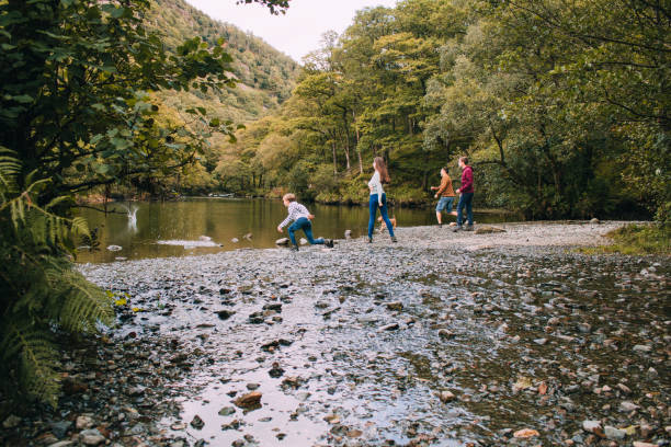 family skimming stones at the lake district - throwing people stone tossing imagens e fotografias de stock