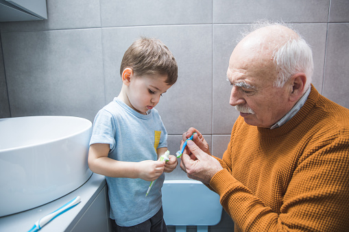 Grandfather and grandson brushing teeth together in the bathroom