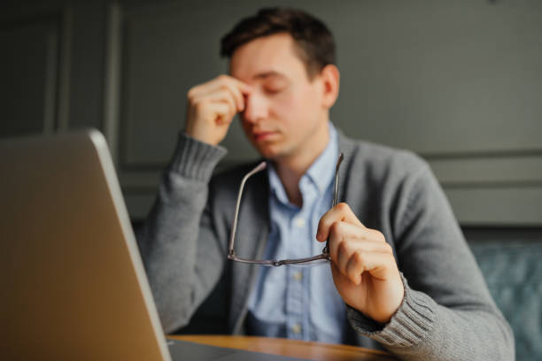 istock Feeling sick and tired. Frustrated young man massaging his nose and keeping eyes closed while sitting while working in cafe. 915677128