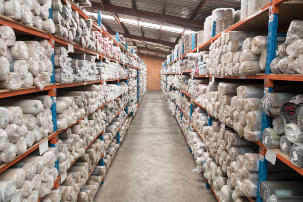 View along aisle in carpet factory warehuose Stacks of rolled up carpets on shelves in storage facility carpet factory stock pictures, royalty-free photos & images