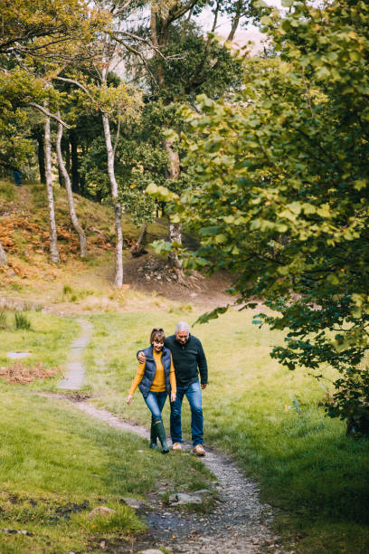 Senior Couple Hiking at the Lake District Senior couple are hiking through woodlands in the Lake District. keswick photos stock pictures, royalty-free photos & images