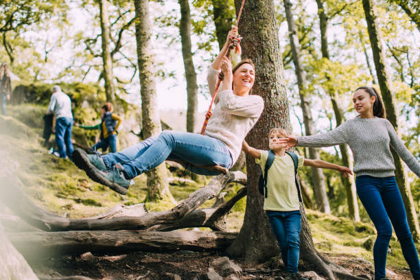 Pushing Mum on the Rope Swing Mature woman is being pushed on a rope swing by her children while they are out on a hike. english lake district photos stock pictures, royalty-free photos & images