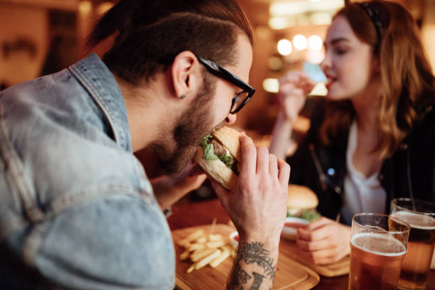 istock Close up of a young man eating burger 915687370