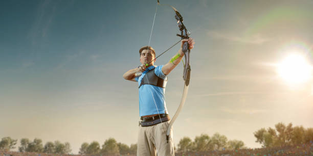 Male archer shooting with the longbow at sunset. Archer in professional field with a lot of fans.