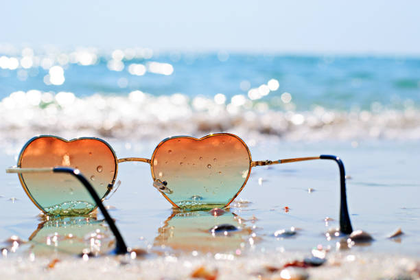 Photo of heart-shaped glasses on the beach Heart-shaped sunglasses on the wet sand, beach at the seaside. Travel and vacation concept beach fashion stock pictures, royalty-free photos & images