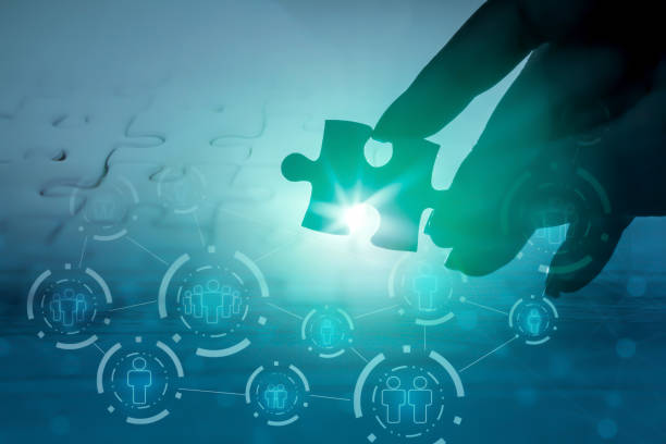 hand holding jigsaw piece with background of teamwork