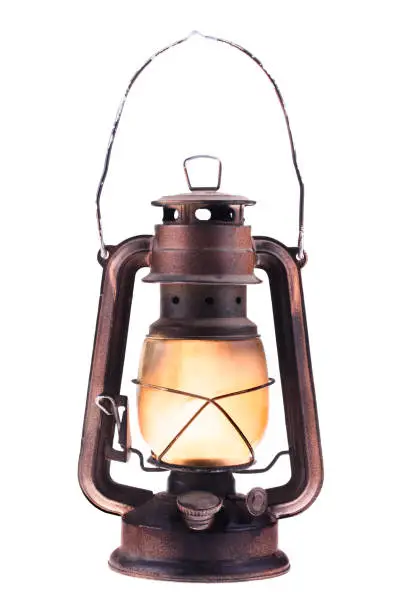Photo of Gas lantern with burning light, isolated on a white background. An antique vintage lamp. Hipster accessory. Camping light. Interior decoration.