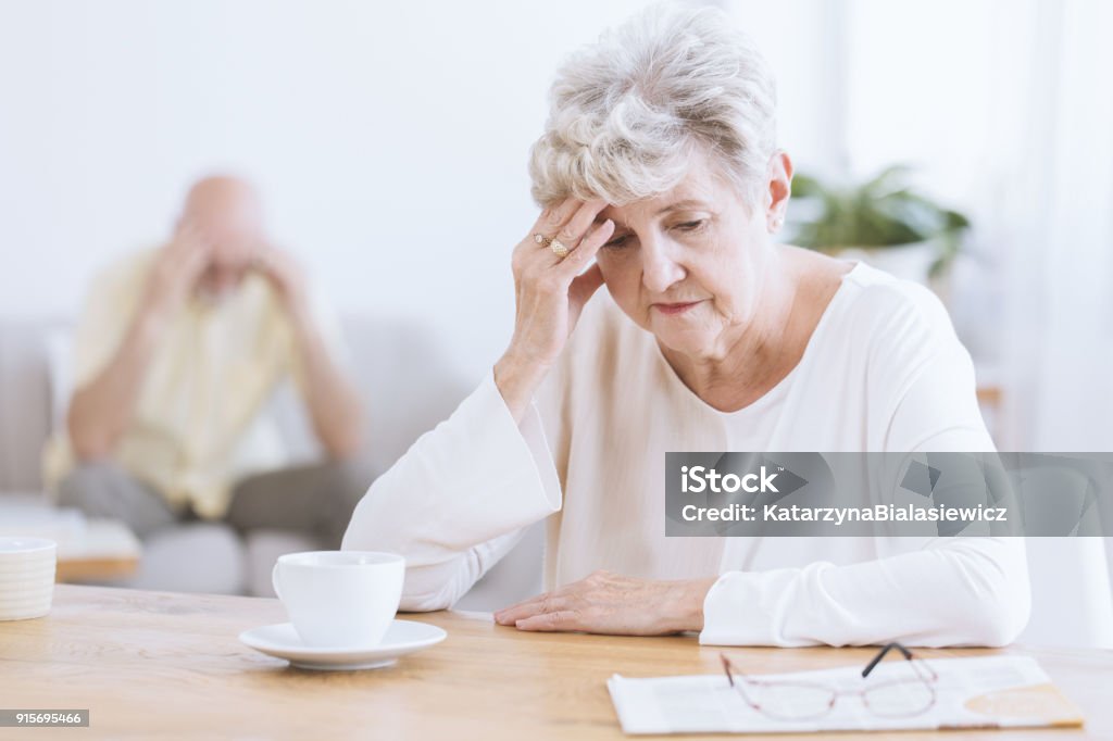Sad senior woman after quarrel Sad senior woman sitting at table after a quarrel with her husband Alzheimer's Disease Stock Photo