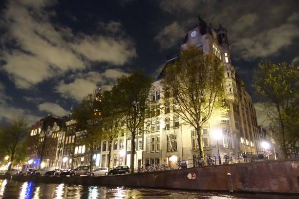 istock Building with clock in Amsterdam seen from canal at night 915697146