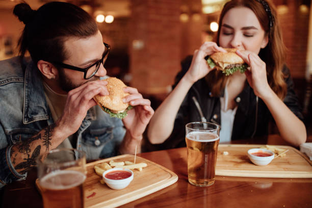 coppia felice che mangia hamburger in una serata di appuntamento - date night foto e immagini stock