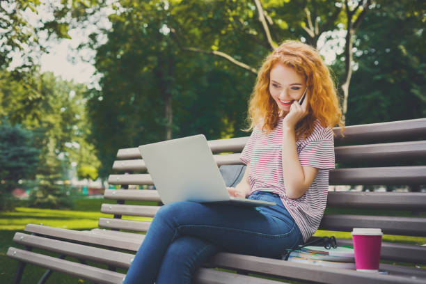 istock Redhead student girl talking on mobile phone and laptop 915704204
