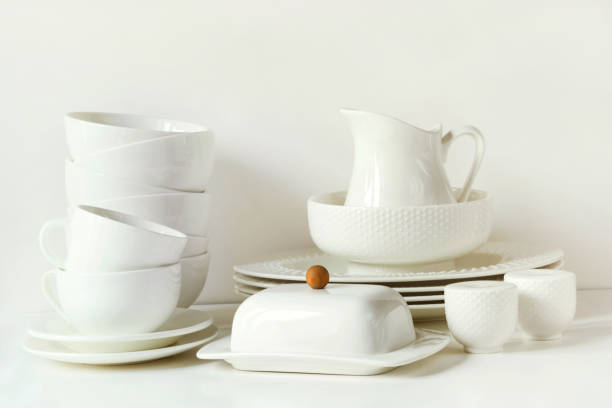 istock White tableware for serving. Crockery,dish, utensils and other different white stuff on white table-top. Kitchen still life as background. Copy space. 915708864
