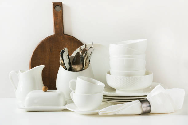 istock White tableware for serving. Crockery,dish, utensils and other different white stuff on white table-top. Kitchen still life as background. Copy space. 915709014