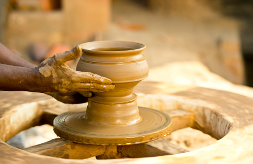 Man forming a clay pot on pottery wheel