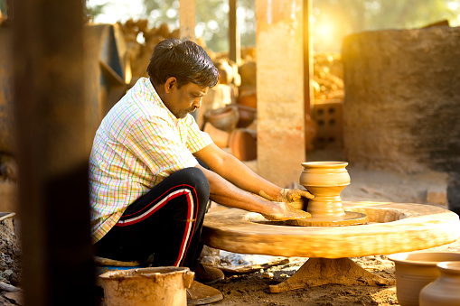 Indian potter molding a clay pot on spinning wheel