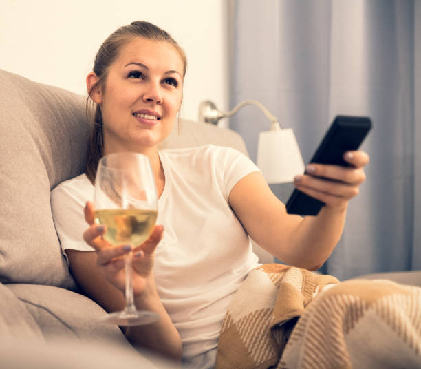 istock Girl is resting with wine and watching TV 915721488