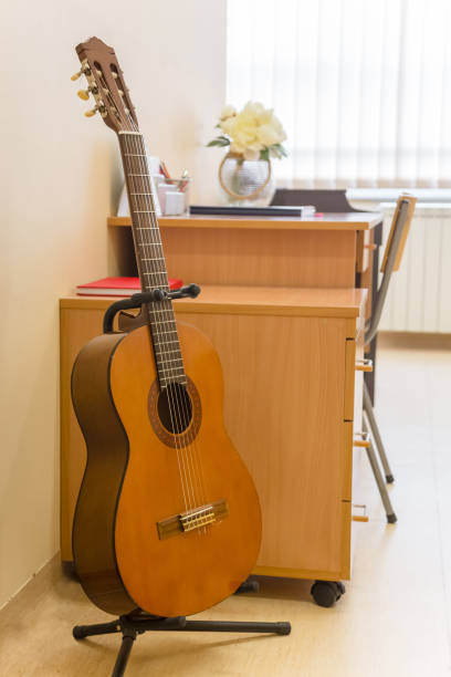 istock Guitar on guitar stand near teachers table in musical classroom 915737004