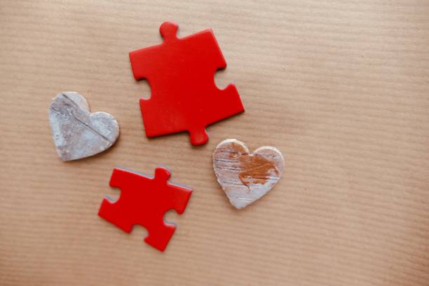istock Two Red puzzle pieces with 2 wooden hearts 915740436
