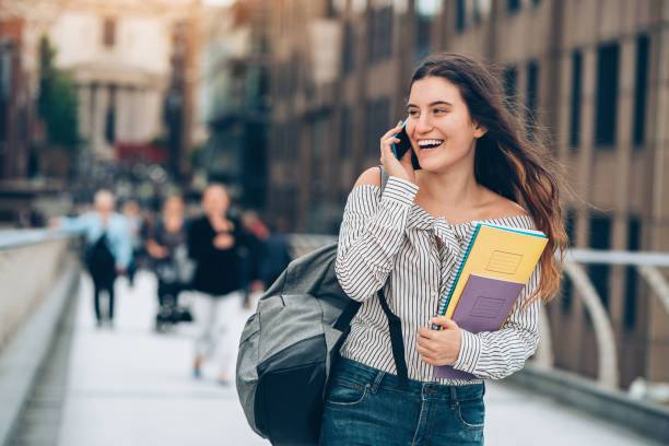 estudiantes caminando y hablando por teléfono - urgent palabra en inglés fotografías e imágenes de stock