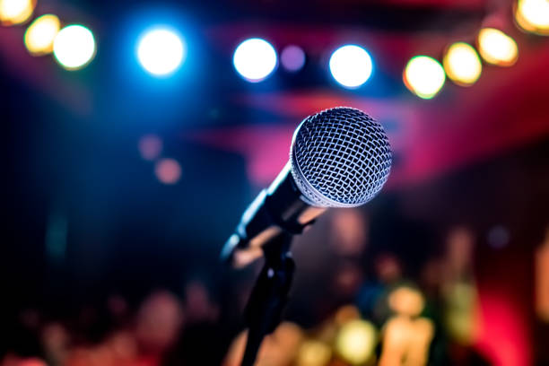 Microphone on stage against a background of auditorium. Public performance on stage Microphone on stage against a background of auditorium. Shallow depth of field. Public performance on stage. singing stock pictures, royalty-free photos & images