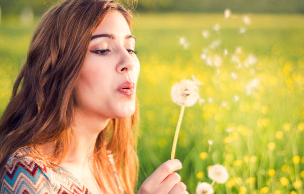 istock Young happy attractive woman playing with dandelion 915747210