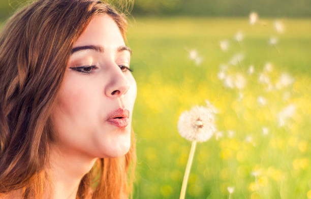 istock Young happy attractive woman playing with dandelion 915747238