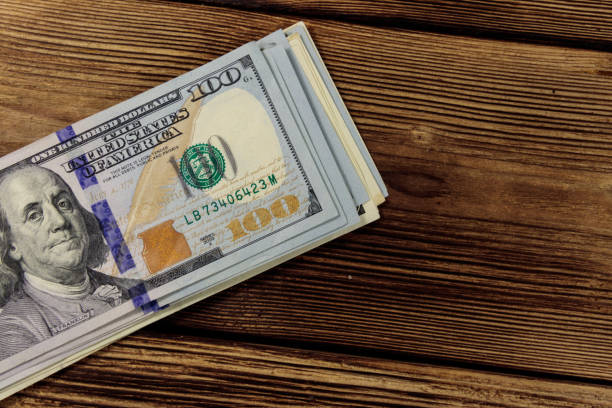 istock Stack of one hundred dollars bills on wooden desk 915748204