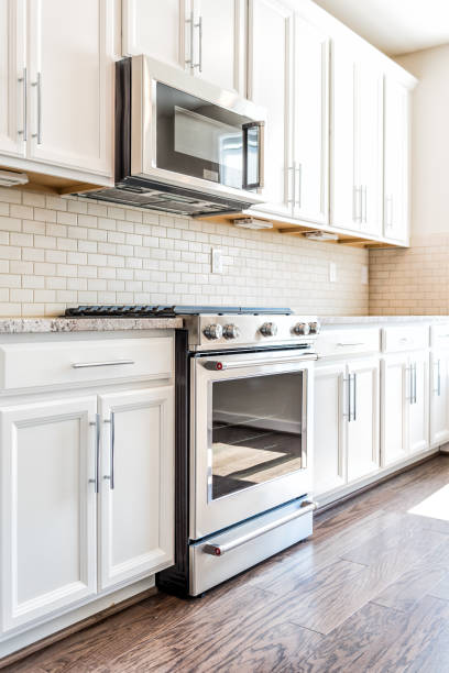 istock Modern gray, brown neutral kitchen features front cabinets with granite countertops and tile backsplash, window in contemporary home, house, apartment 915749632