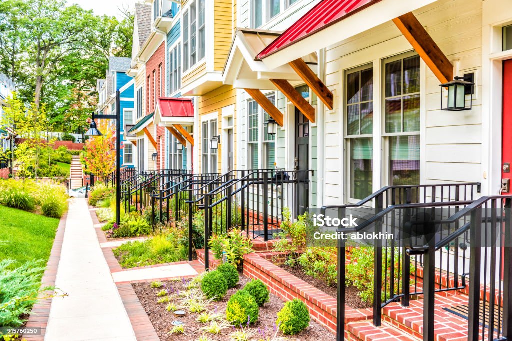 Row of colorful, red, yellow, blue, white, green painted residential townhouses, homes, houses with brick patio gardens in summer Residential Building Stock Photo