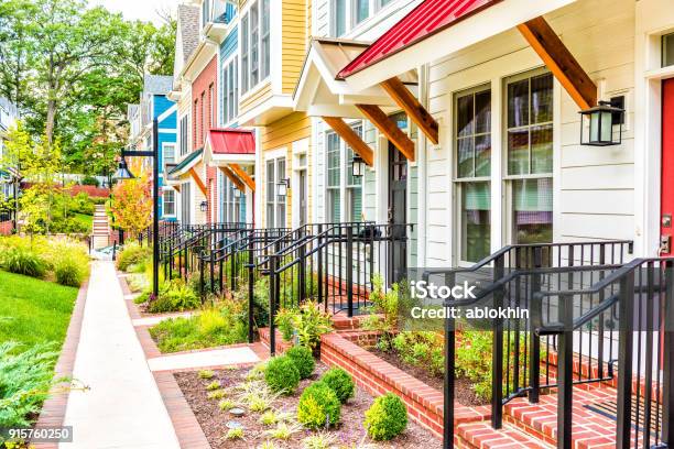 Row Of Colorful Red Yellow Blue White Green Painted Residential Townhouses Homes Houses With Brick Patio Gardens In Summer Stock Photo - Download Image Now