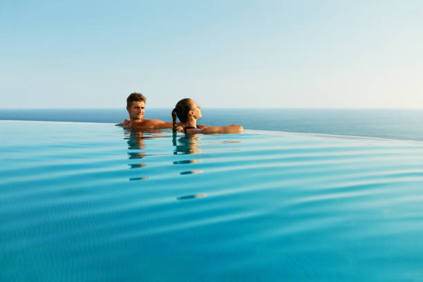 Couple In Love In Luxury Resort Pool On Romantic Summer Vacation Couple In Love At Luxury Resort On Romantic Summer Vacation. People Relaxing Together In Edge Swimming Pool Water, Enjoying Beautiful Sea View. Happy Lovers On Honeymoon Travel. Relationship, Romance infinity pool stock pictures, royalty-free photos & images