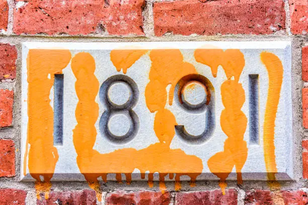 Closeup of 1891 number sign on brick building with colorful paint