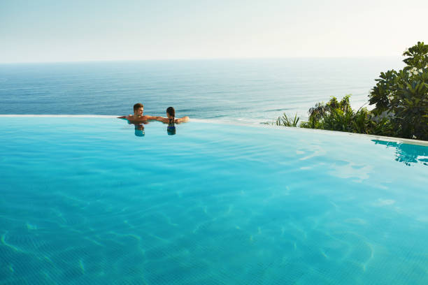 vacanza romantica per coppia innamorata. persone in piscina estiva - infinity pool foto e immagini stock
