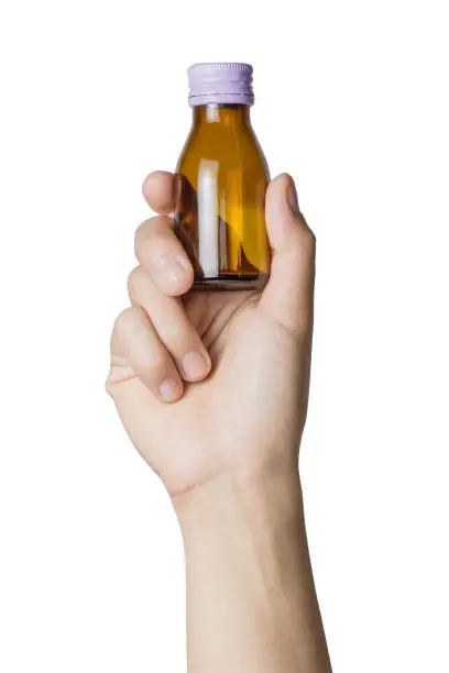 Photo of Woman's hand holding empty small brown medicine bottle liquids transparent on white background. File contains a clipping path.