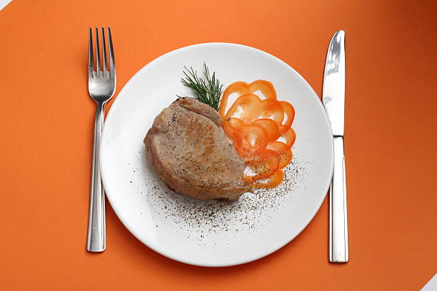 Meat and pepper on white plate with orange background stock photo