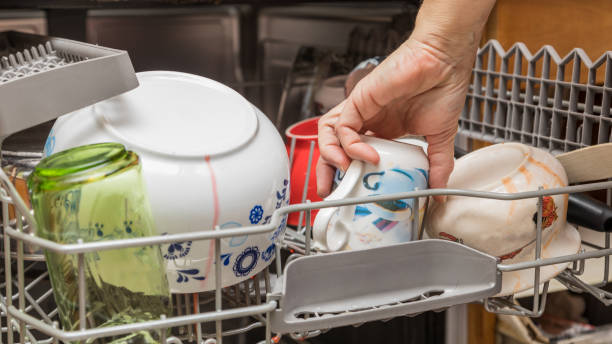 One hand loads a dishwasher stock photo