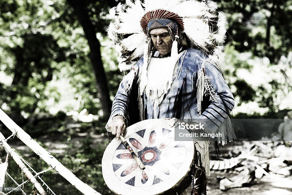 Chief Horizontal portrait of a Native American Chief wearing a feathered head dress and playing an instrument. Indigenous Peoples of the Americas Stock Photo