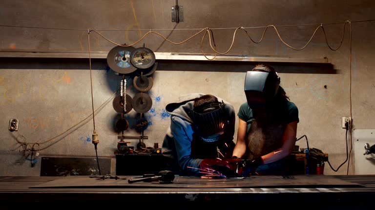 Engineer teaching apprentice to use welding machine